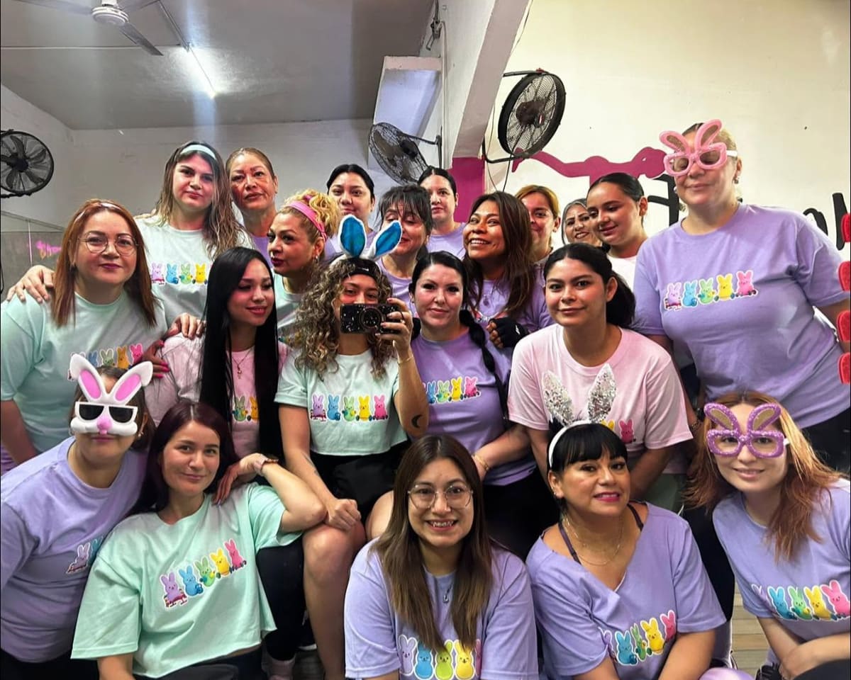 Alumnas con playeras de conejitos de colores y orejas de Pascua, en una selfie frente al espejo del gym