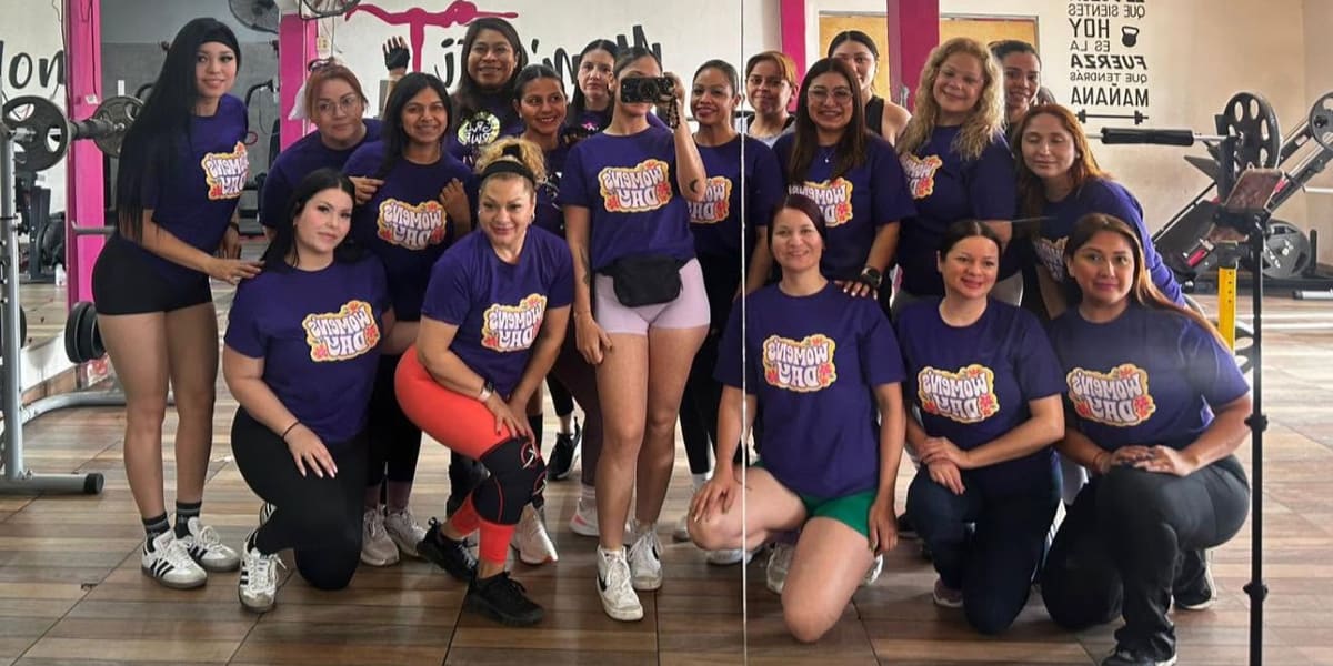 Alumnas con la playera morada del Día de la Mujer, en una selfie frente al espejo del gym